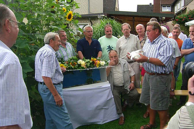 Zuchtfreunde im Garten um einen Korb mit weißen Tauben